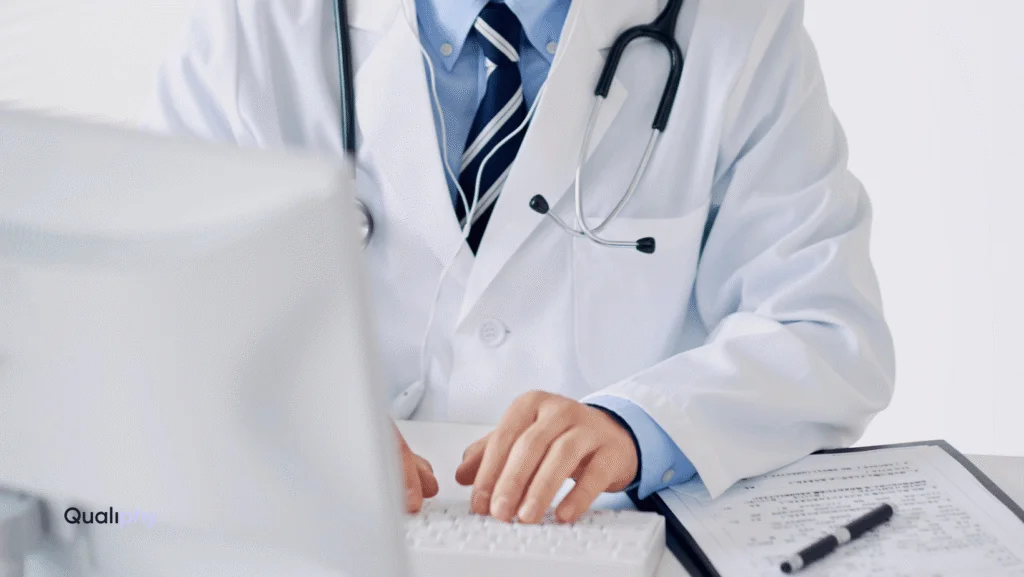 Alt Text: A medical professional in a white coat with a stethoscope types on a keyboard next to a patient chart, representing a telehealth Good Faith Exam.